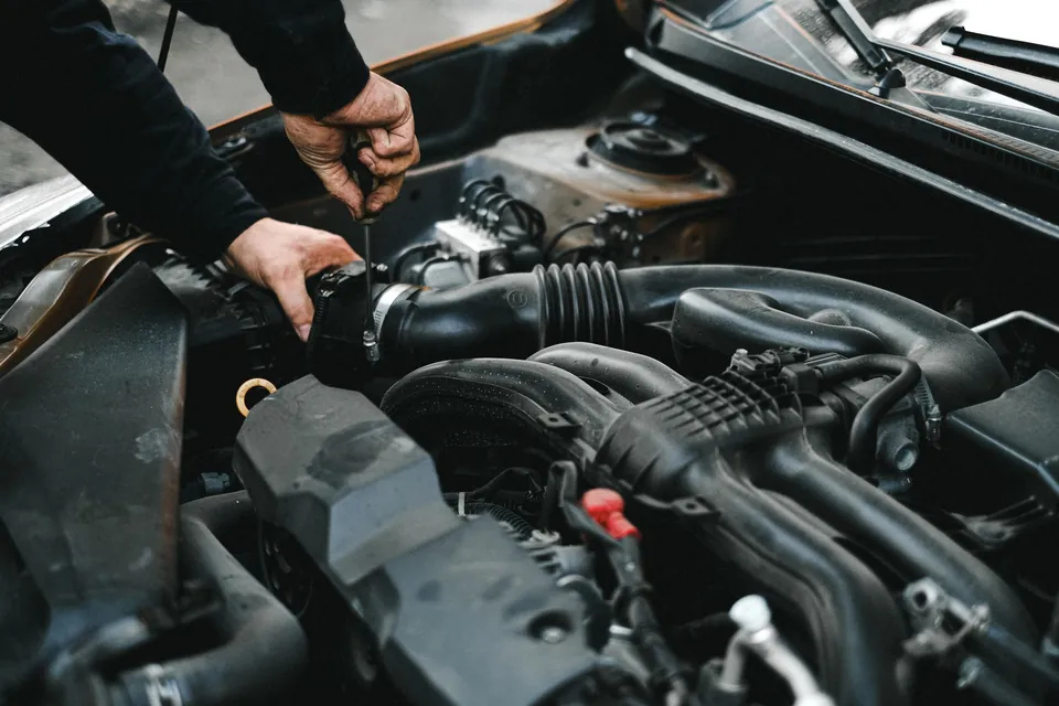 Dłonie mechanika przy przewodach w komorze silnika