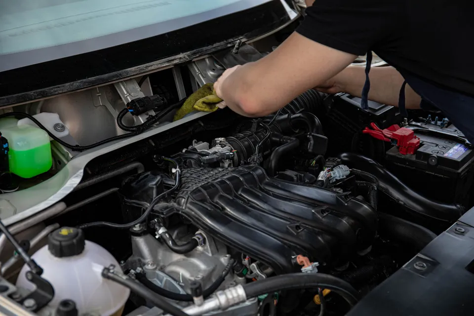 Mechanik pochylony nad komorą silnika, widać ramię i cały silnik z góry
